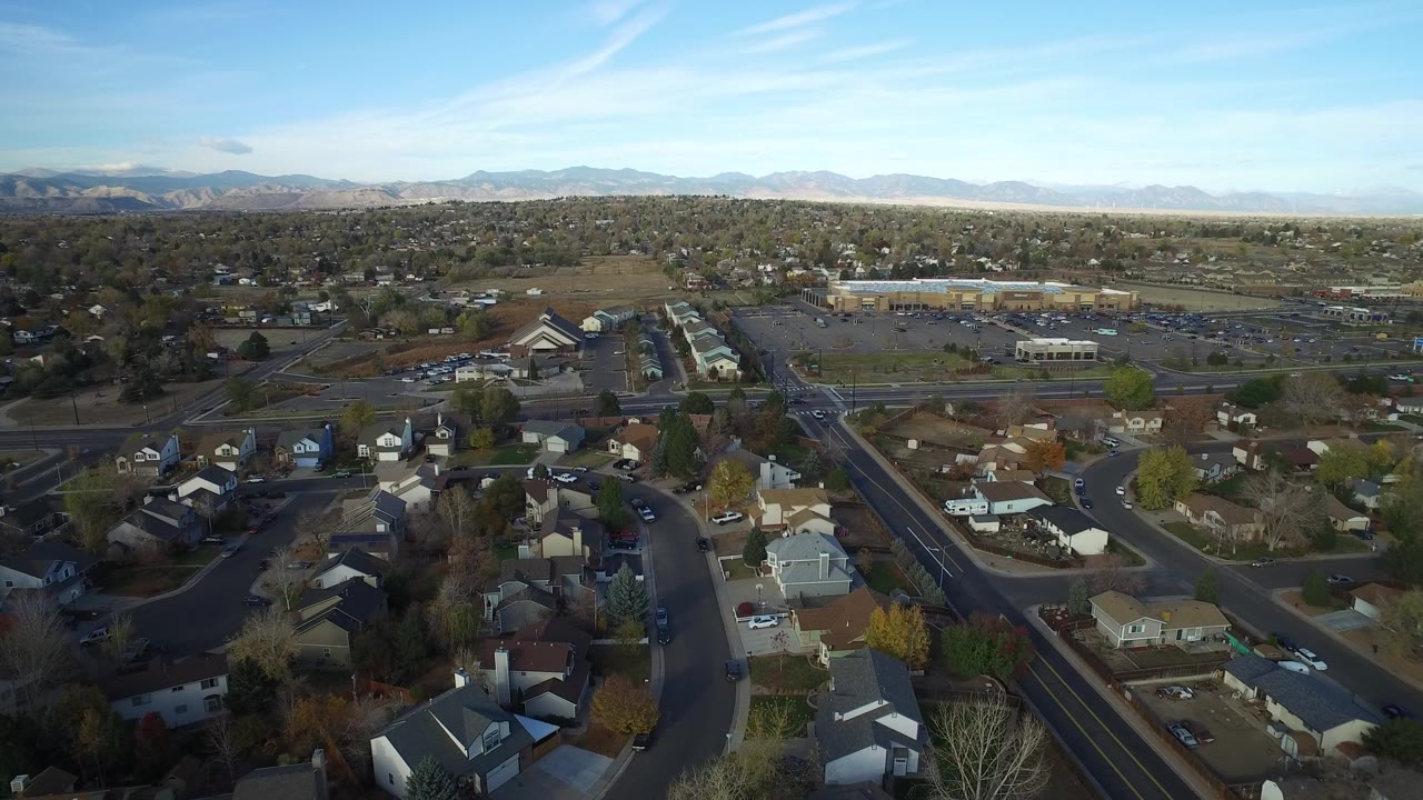 Aerial view of suburban roads, houses, trees, and distant mountains.