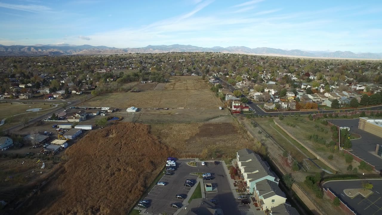 Suburban neighborhood and dry fields seen from above under blue sky