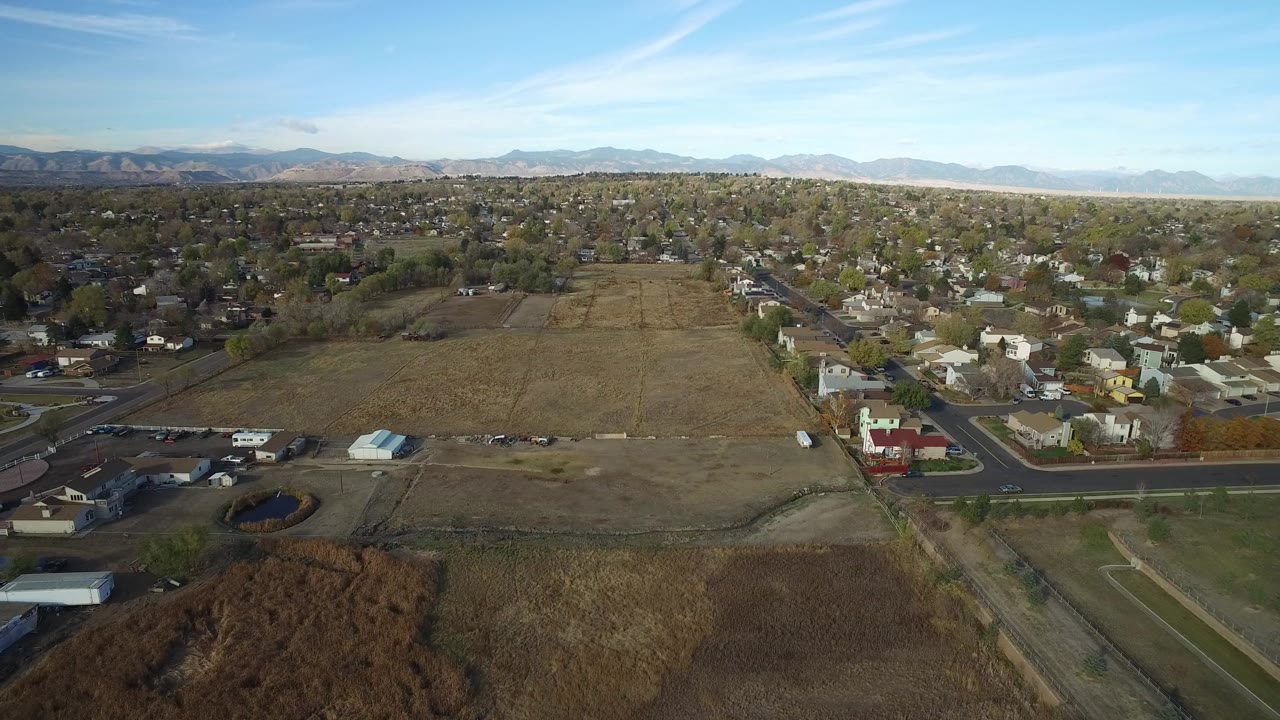 Aerial view of a dry field beside suburban homes and roads.