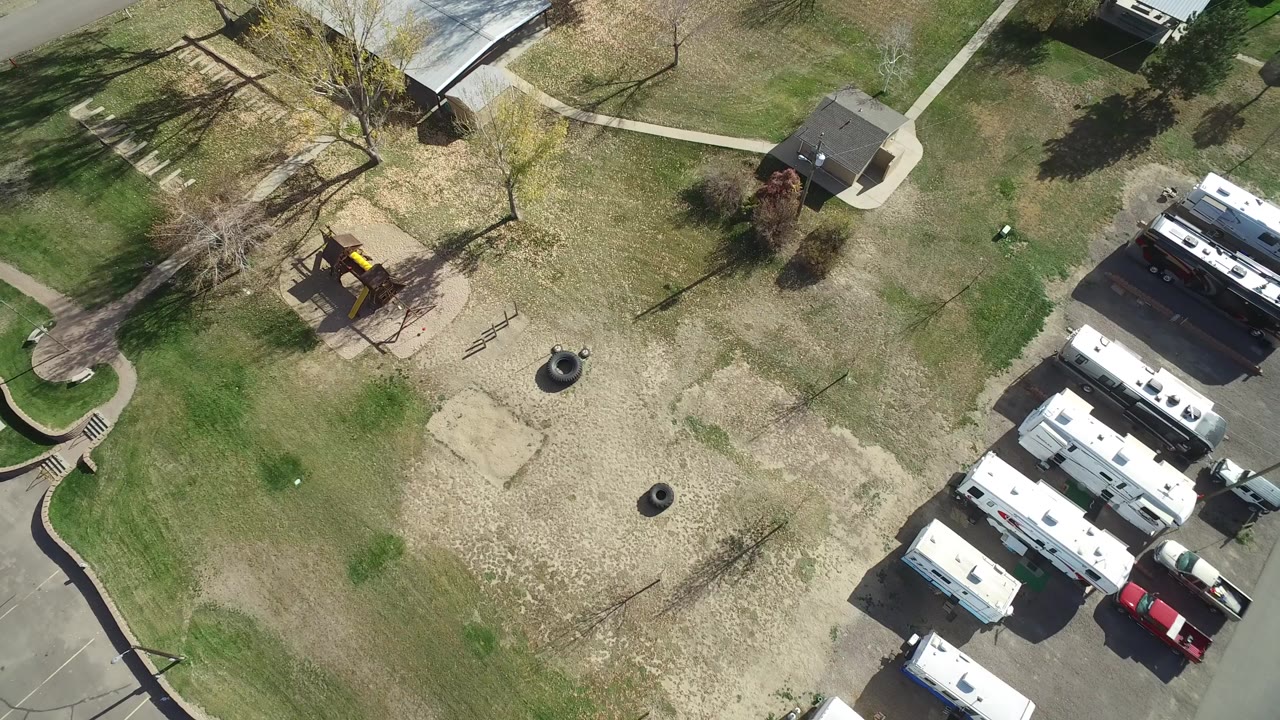 Aerial view of a grassy park beside parked trailers and homes.