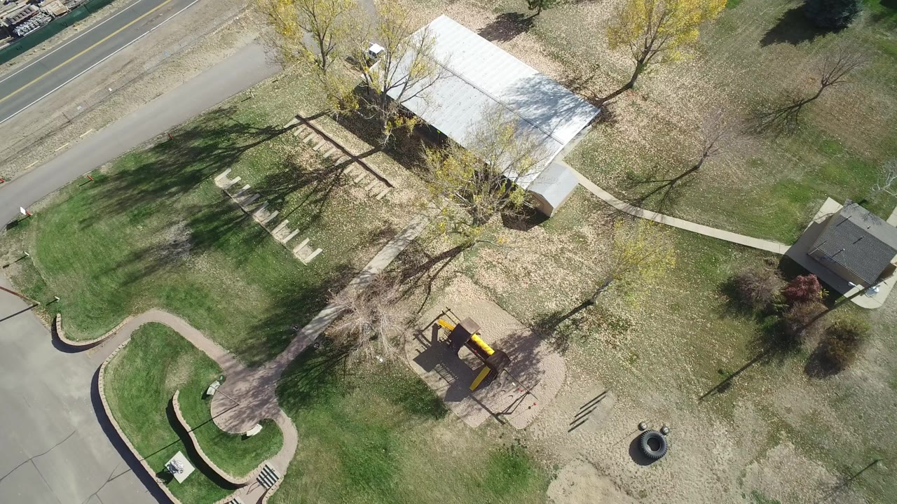 Overhead view of a road, lawns, trees, sidewalk, and playground.