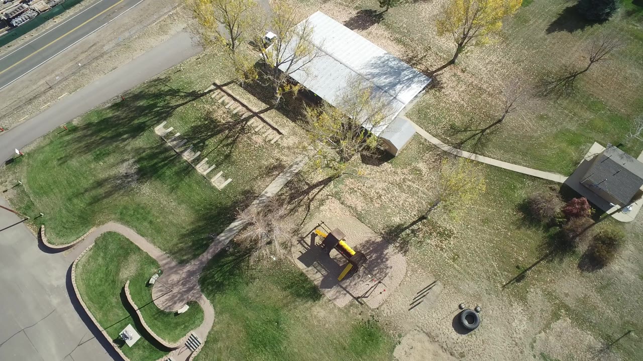 High aerial frame in Hidden Lake, Colorado with a white-roofed building near the upper right, lawn sections, sidewalks, a road, trees, and no visible people.