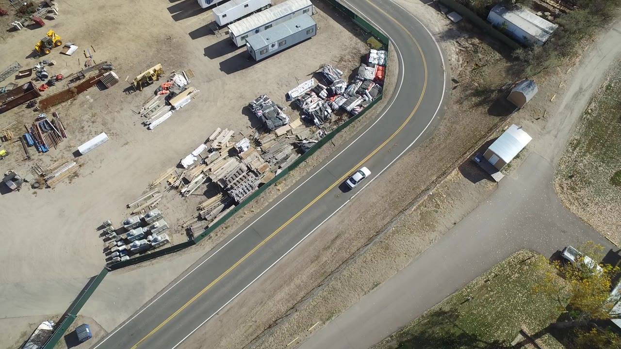 Overhead view of an industrial yard beside a curved road.