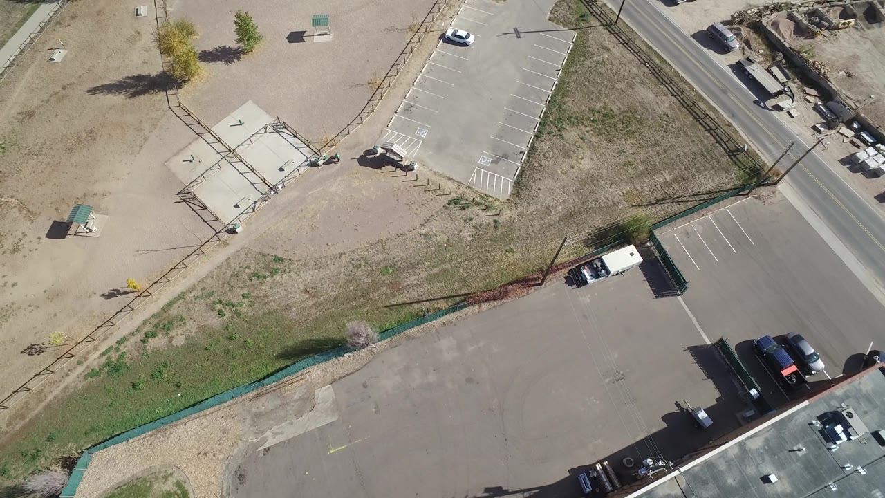 Top-down view of sparse parking lots and a road with vehicles.