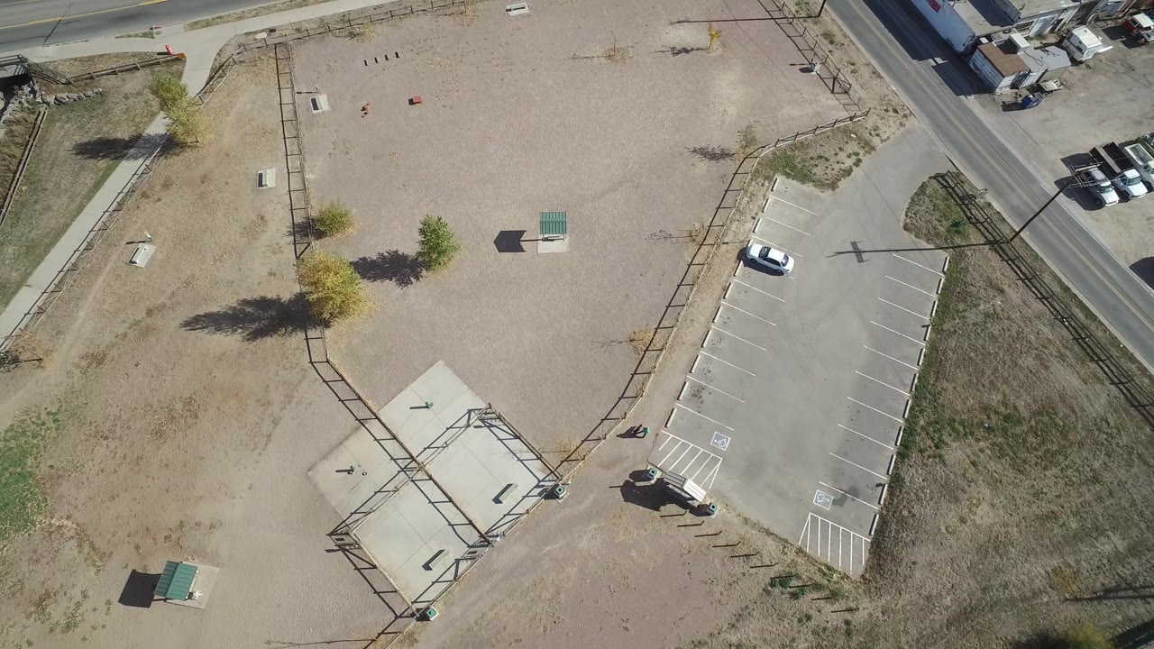 Top-down view of a mostly empty parking lot beside dry terrain.