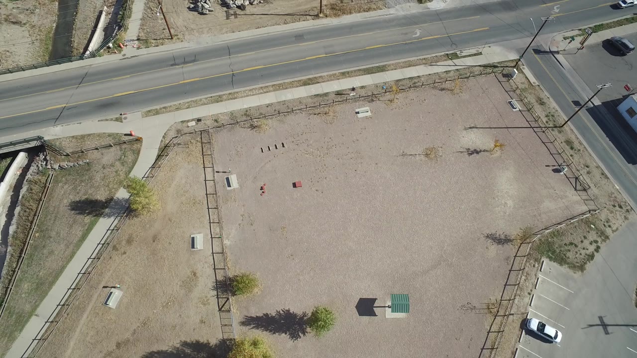 Top-down road and gravel lot with a crosswalk near the corner.