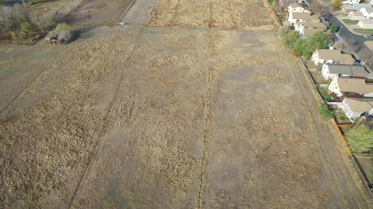 Overhead view of brown field beside light-colored homes