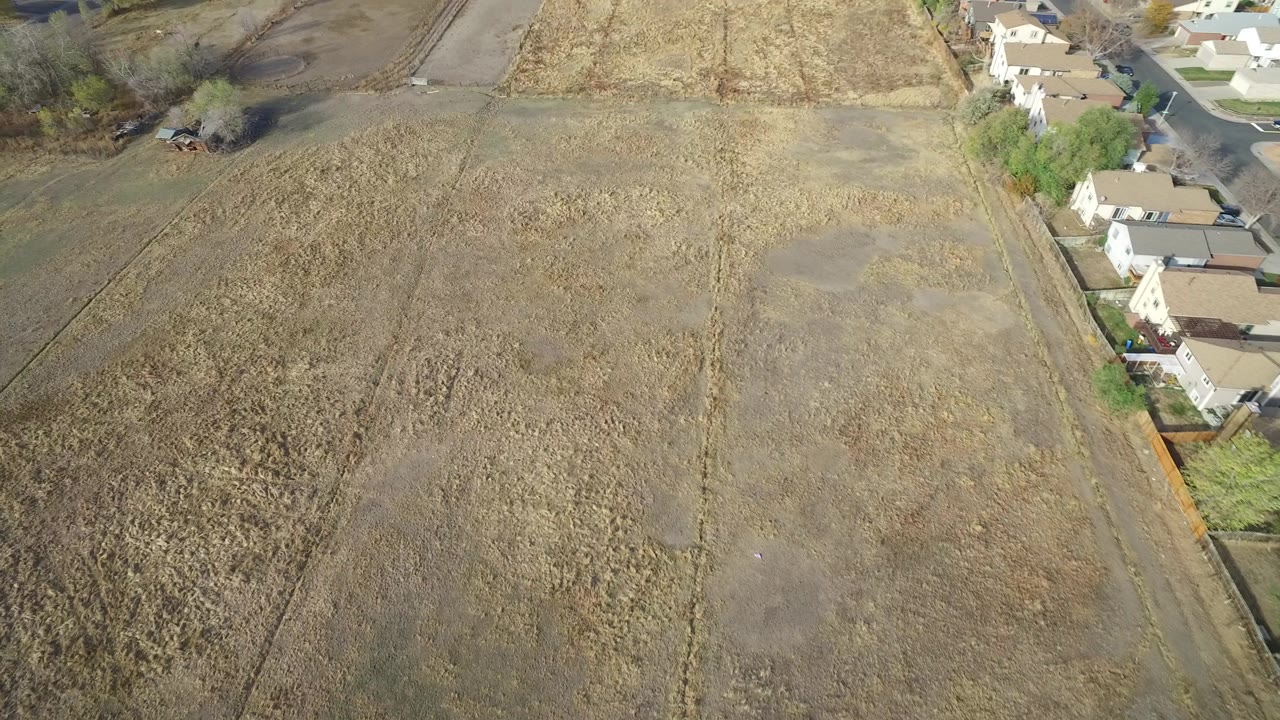Second frame holds a high aerial view over dry tan field sections in Hidden Lake, Colorado, with a row of homes on the right and no visible people.