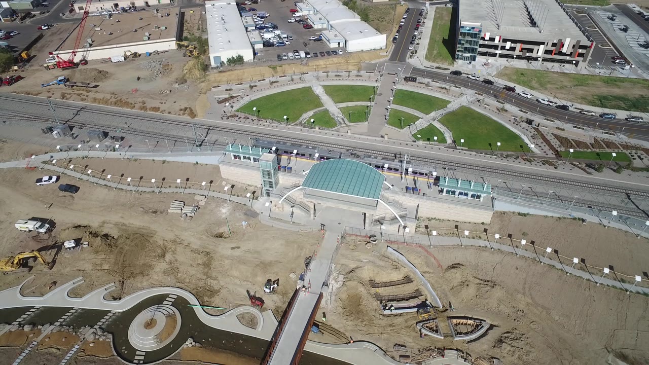 Aerial view in Hidden Lake, Colorado, with the teal-roofed building centered near rail tracks, bare construction soil in the foreground, and no visible people.