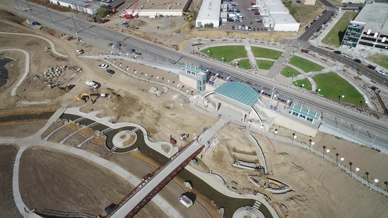 Aerial view of a rail station, roads, paths, lawns, and construction ground.