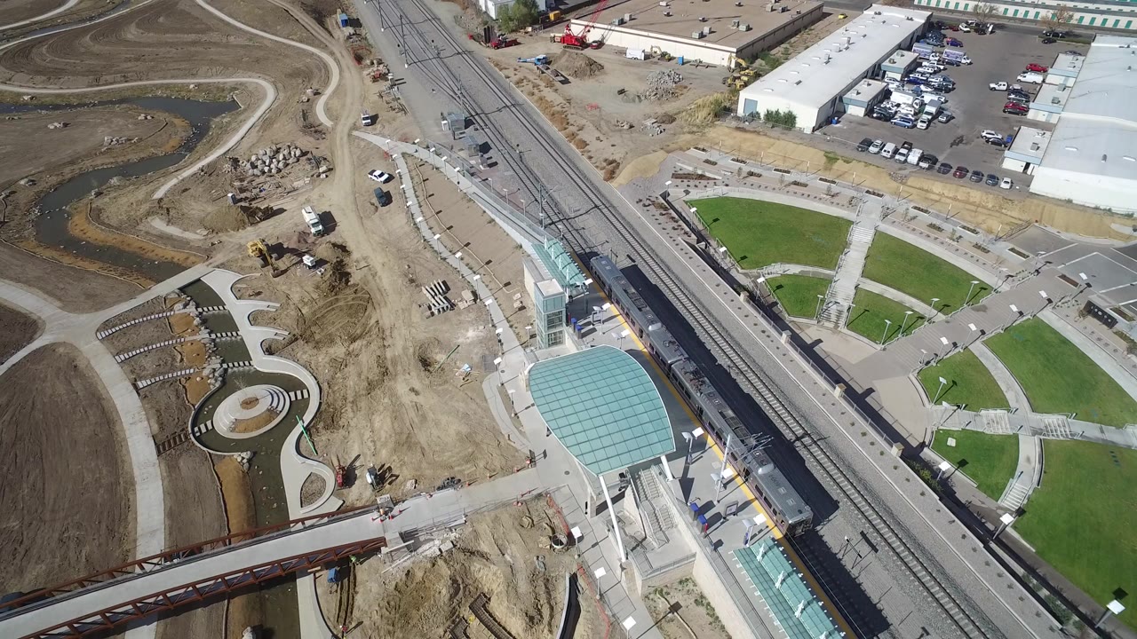 Aerial view of rail tracks beside sports fields and a parking lot.