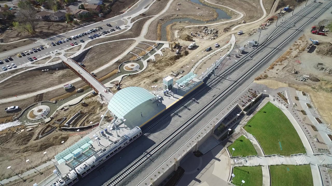 Aerial view of a domed rail station with a train beside tracks and roads.