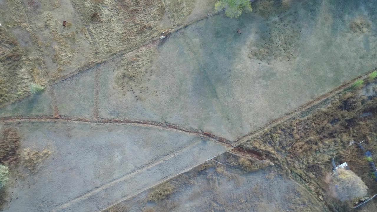 Hidden Lake, Colorado aerial frame with muted green terrain, a diagonal path or drainage line, brown vegetation along one side, and no visible people.