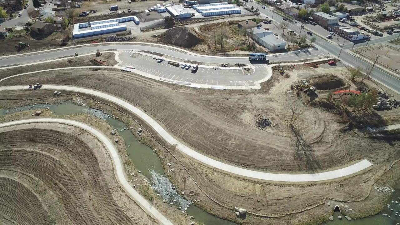 Hidden Lake, Colorado aerial view centered on the long curved path and canal, with parking spaces, a road, and small buildings in the background and no visible people.