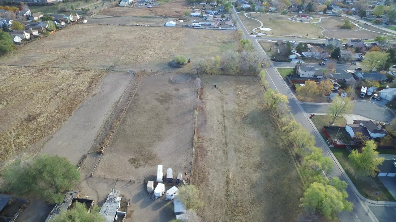 Aerial view of open fields beside a road and houses.