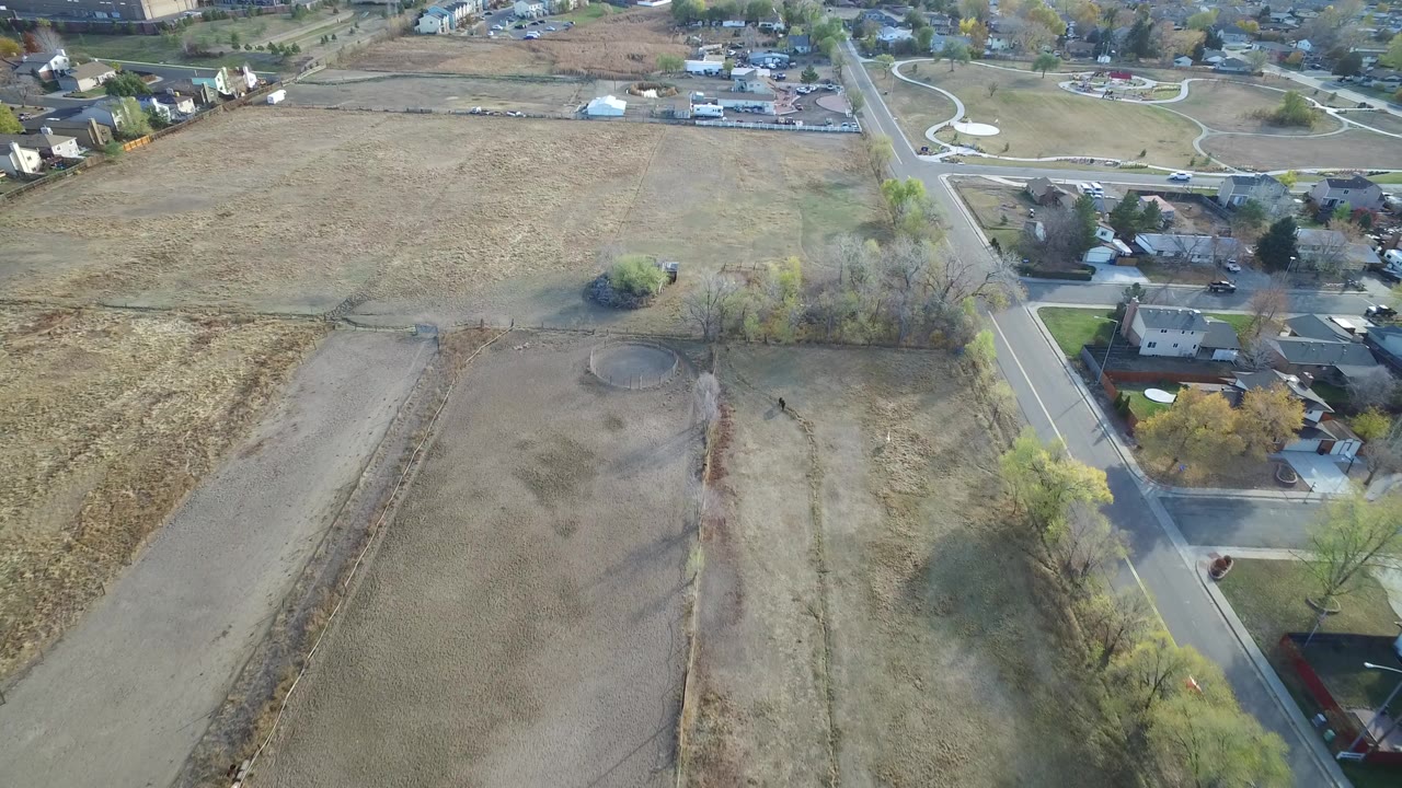 Aerial view of open lots beside a residential road and houses.