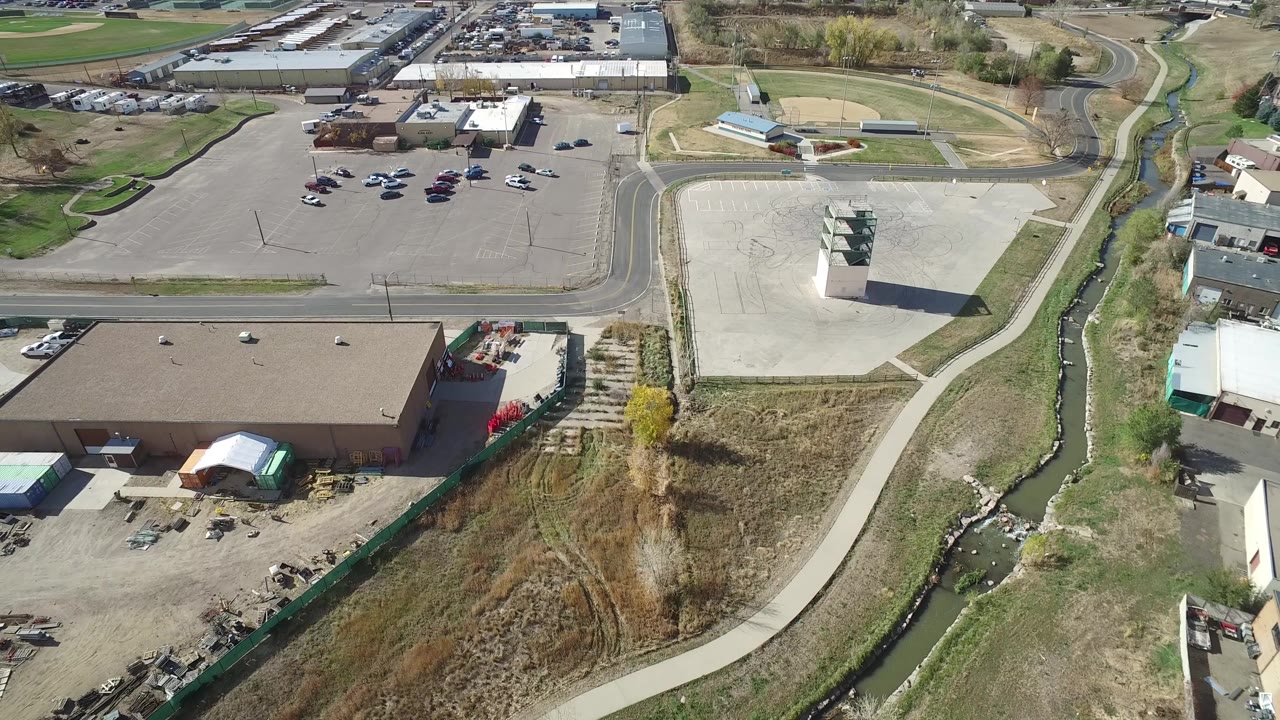 Aerial view of industrial building, parking lots, roads, creek, and grass.