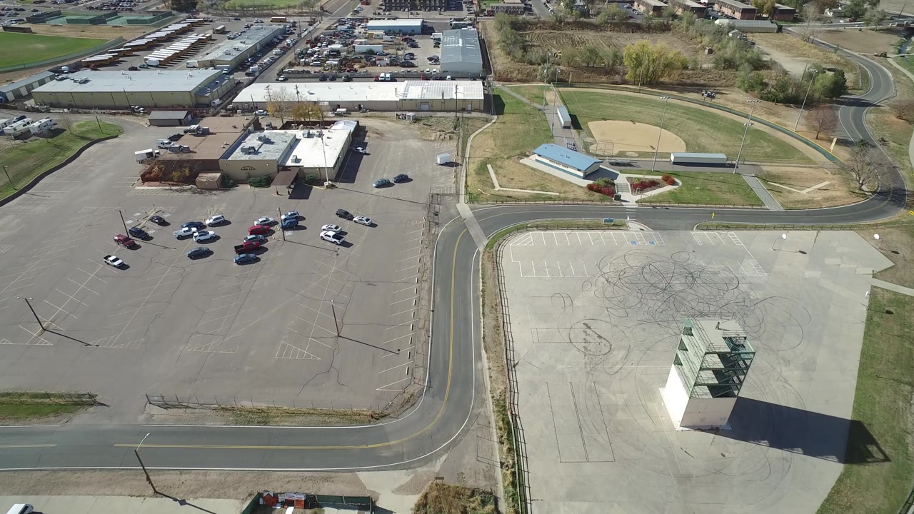 Aerial view of parking lots, roads, a baseball diamond, and marked pavement.