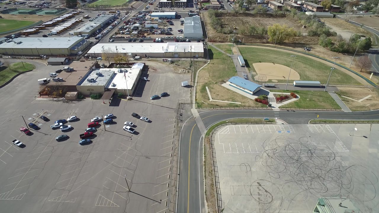 Aerial view of parking lots, industrial buildings, and a baseball field.