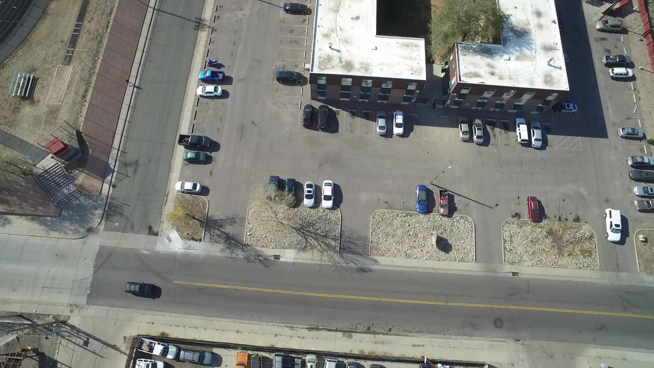 Overhead view of a commercial building, parking lot, and bordering streets.