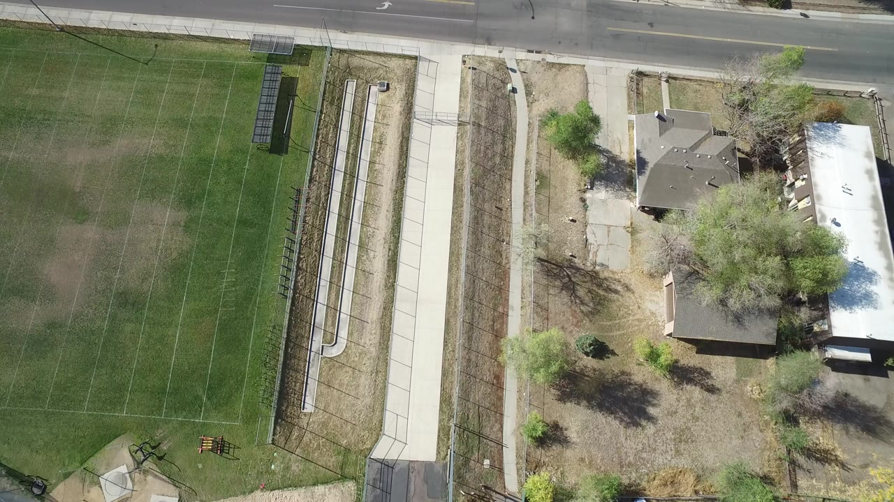 Overhead view of a road beside a grass field and nearby homes.