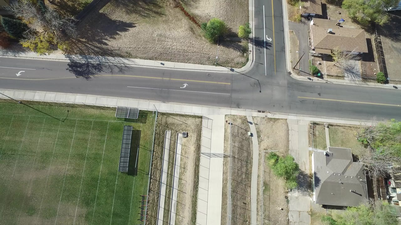 Overhead view of a two-lane road beside lawns and houses.