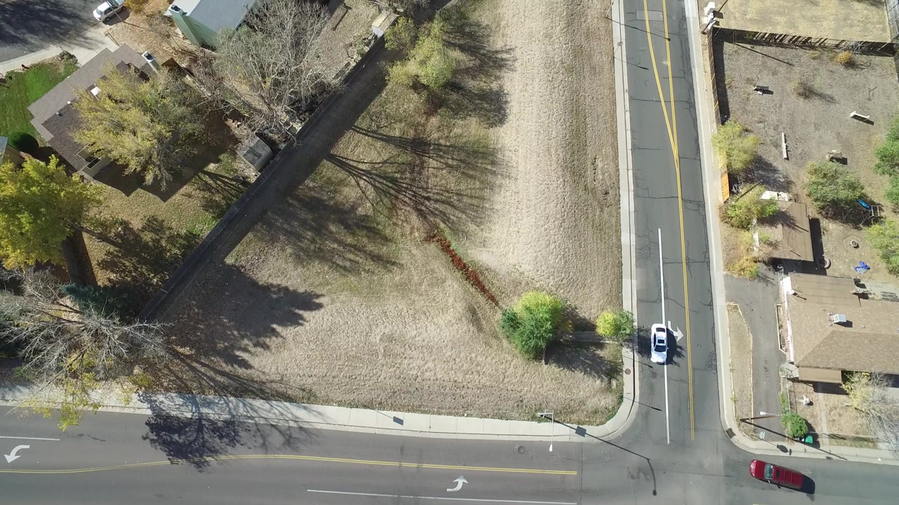 Top-down suburban streets with a red car, a white vehicle, homes, yards, and trees.