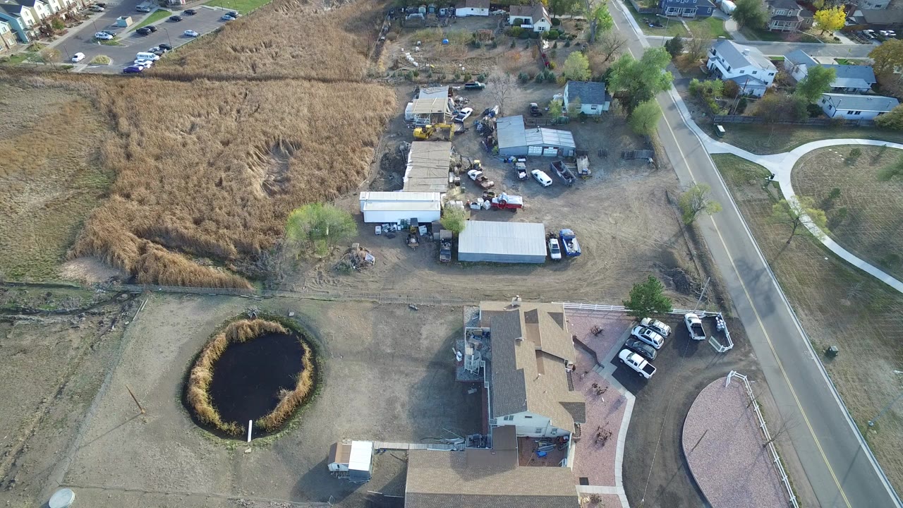 Aerial view of homes, road, open lots, and small pond
