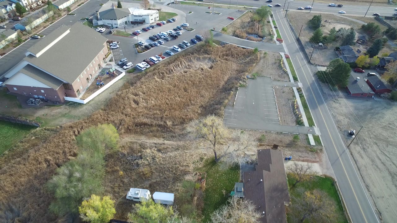Elevated view of a roadside building, parking lot, dry field, and traffic lanes.
