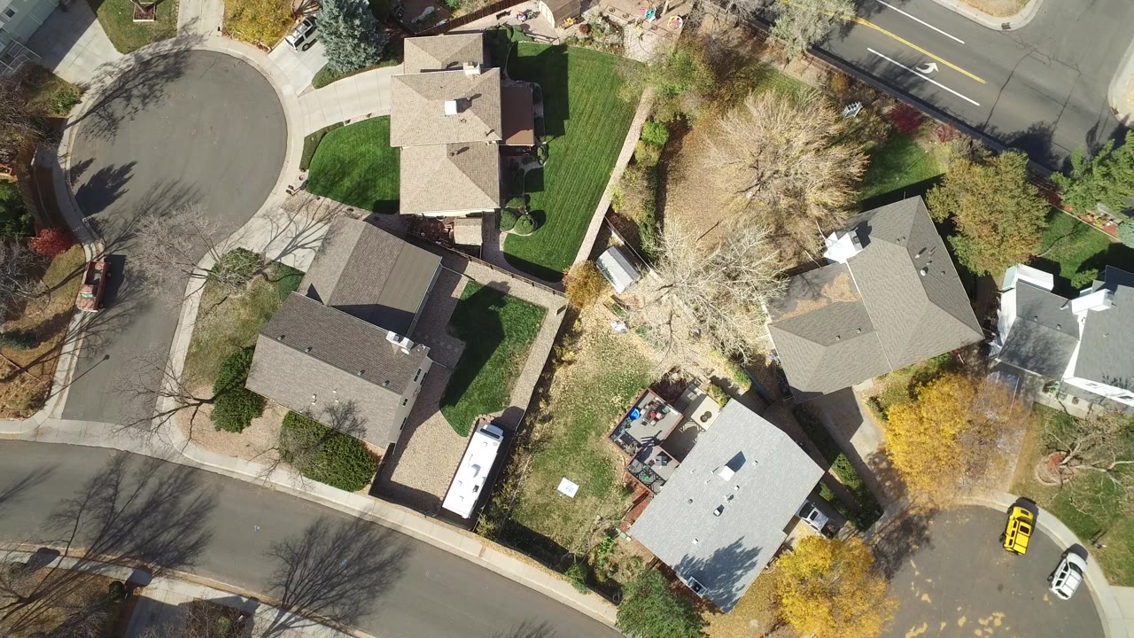 Overhead view in Hidden Lake, Colorado, with a cul-de-sac at left, several roofs, green lawns, bare trees, and a white vehicle along a residential street.
