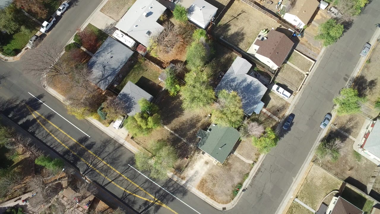 Overhead residential block with houses, streets, trees, and parked cars.