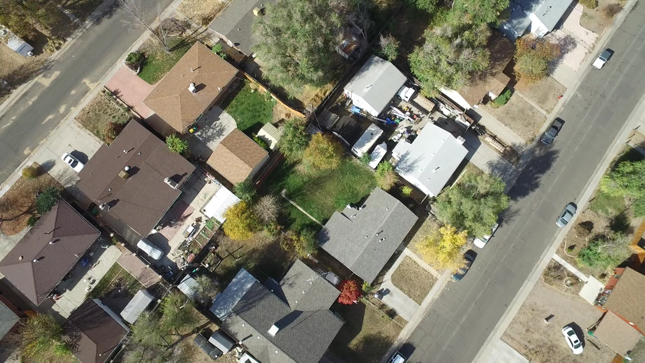 Top-down aerial frame over Hidden Lake, Colorado showing several detached homes, tree canopies, sidewalks, parked cars, and no visible people.