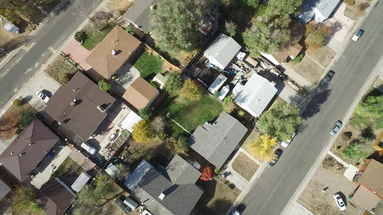 Near-vertical aerial over Hidden Lake, Colorado with brown and gray rooftops, fenced yards, mature trees, a diagonal residential road, and no visible people.