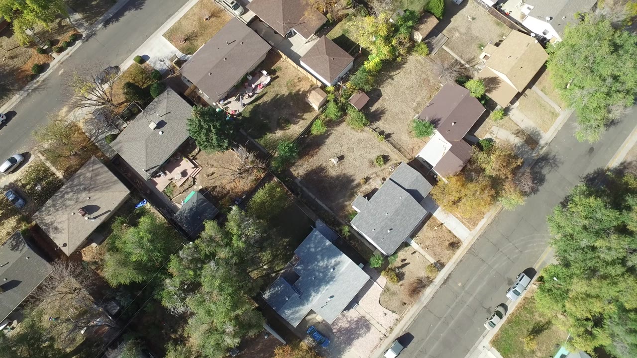 Top-down suburban street with homes, trees, and parked cars