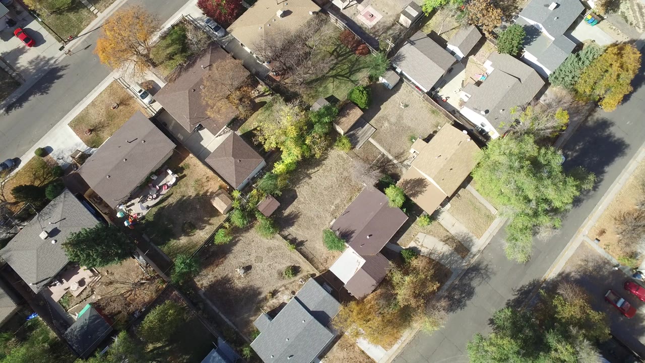 Overhead frame of Hidden Lake, Colorado homes with fenced yards, autumn trees, a curved residential street, parked cars, and no visible people.