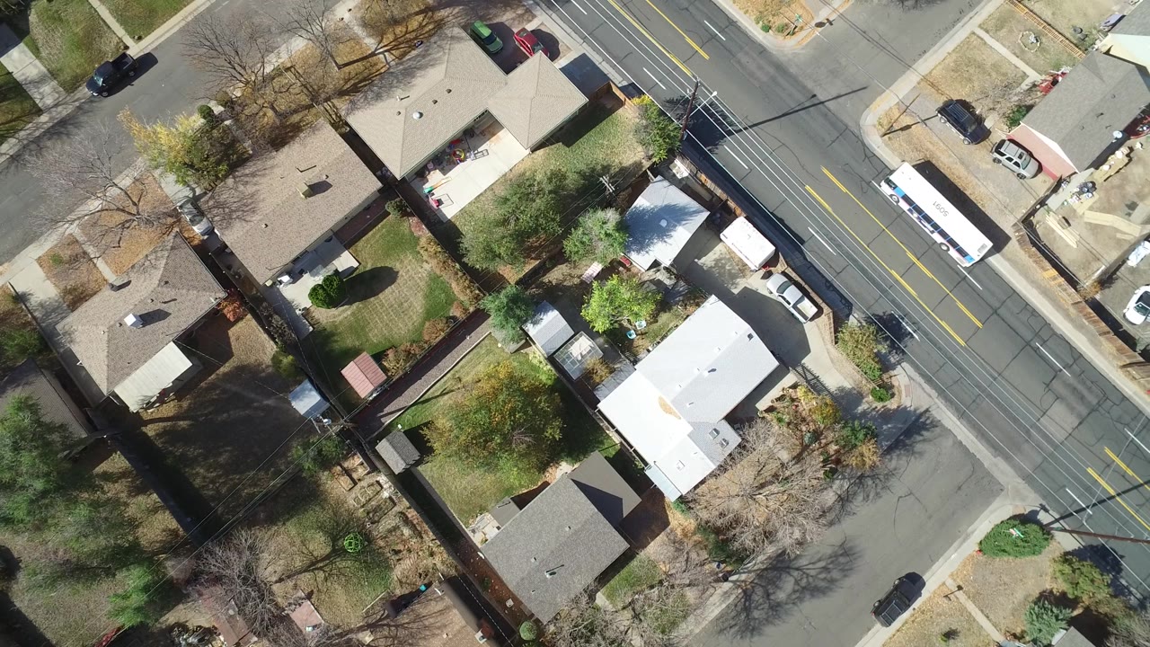 Bird's-eye view of houses and a road with a white bus near the upper right.
