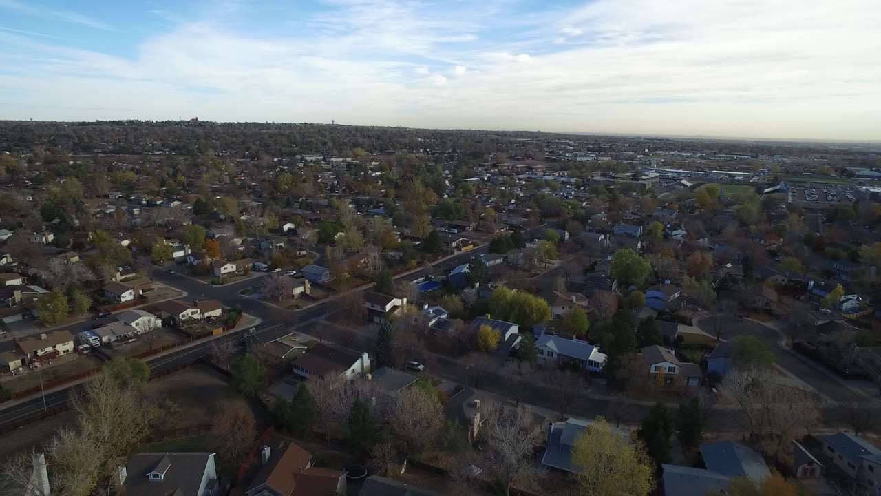 Hidden Lake, Colorado aerial view with a slightly advanced look over low houses, curving streets, tree cover, distant development, and no visible people.