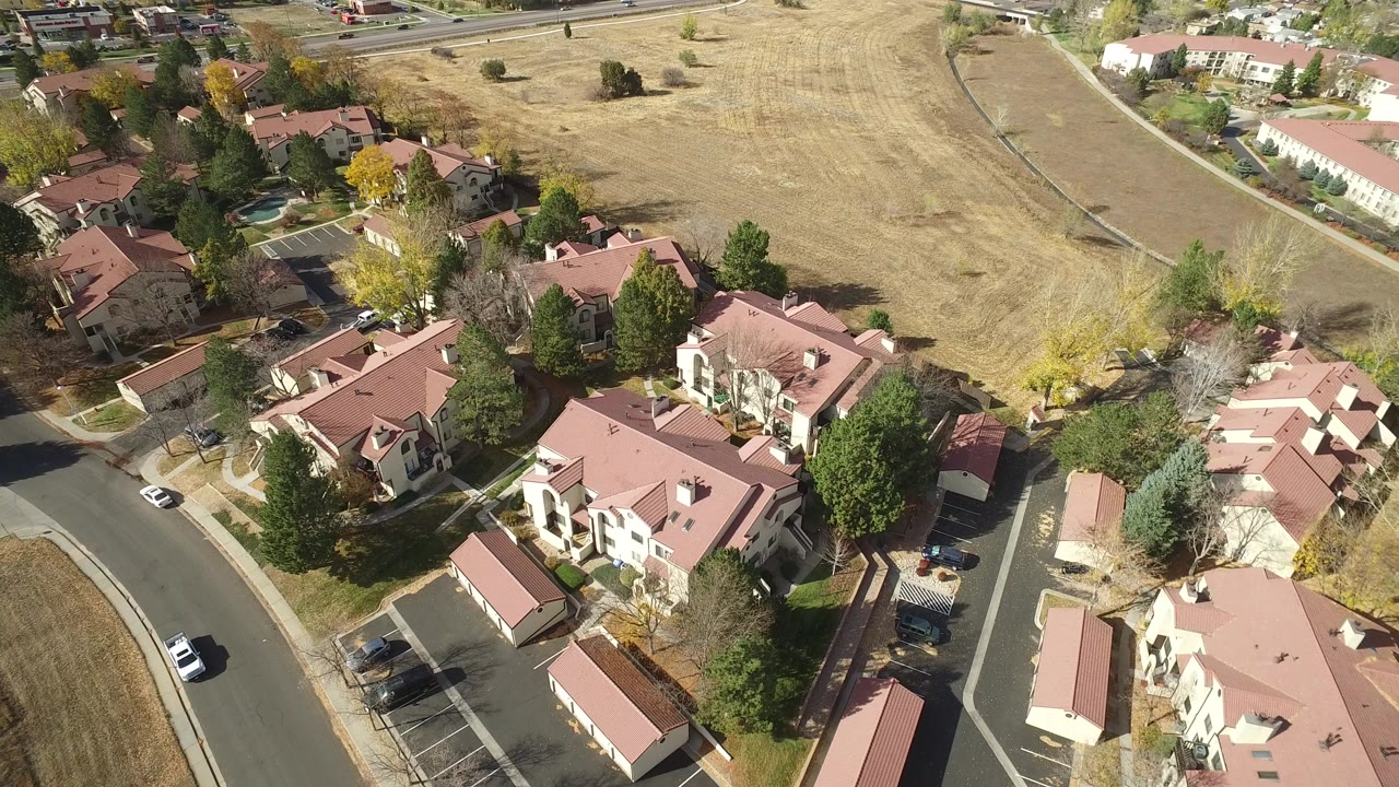 Aerial view of red-roofed residential buildings beside dry open grassland.