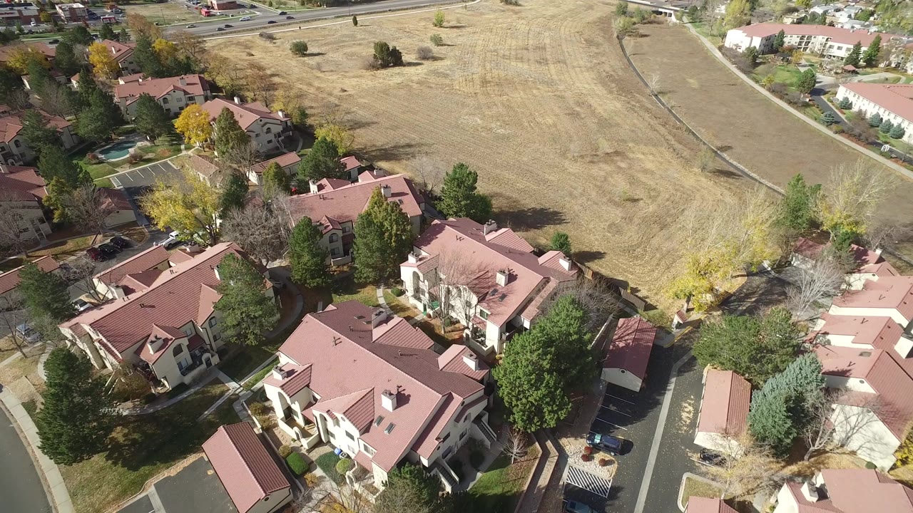 Drone-like view across houses and a broad grass field.