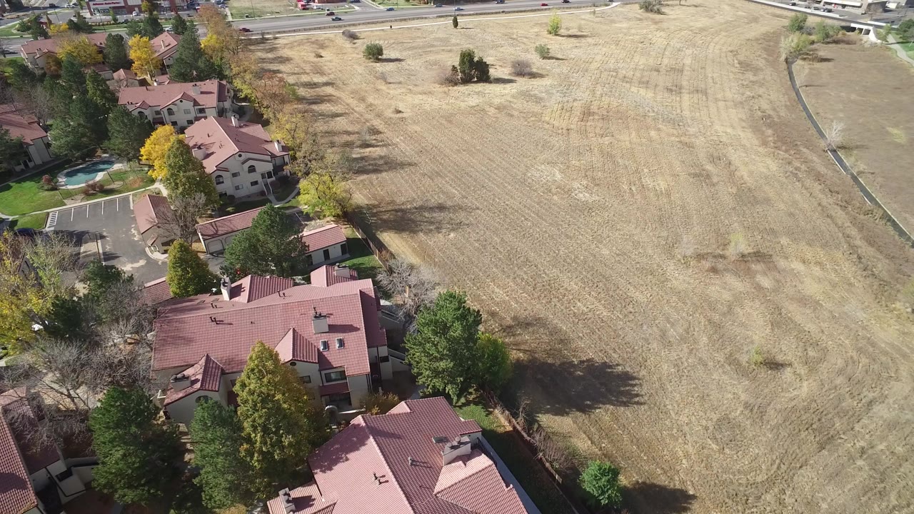 Aerial view of red-roofed houses beside a large dry field.