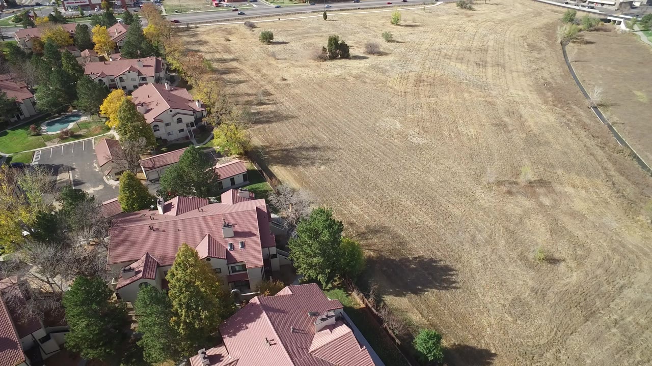 Hidden Lake, Colorado aerial view with clustered homes and trees on the left and the dry field spreading to the right, with no discernible faces.