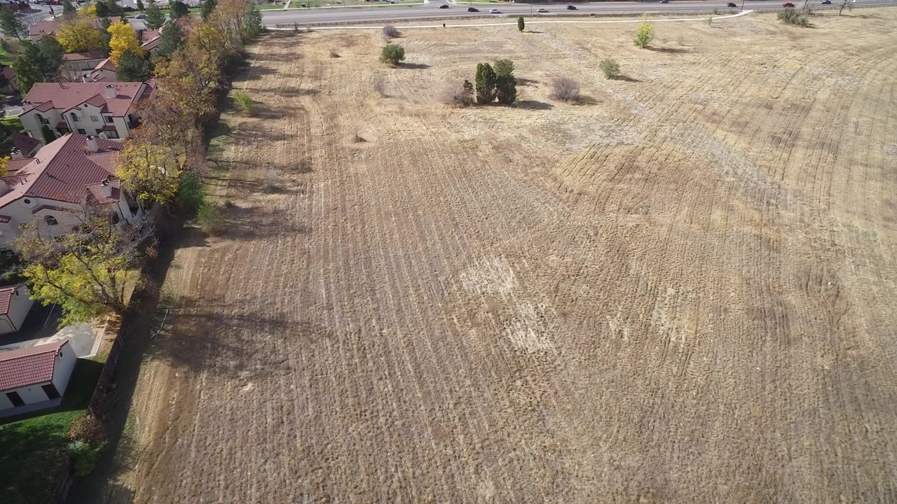 Aerial view of a dry open field beside homes and a road.