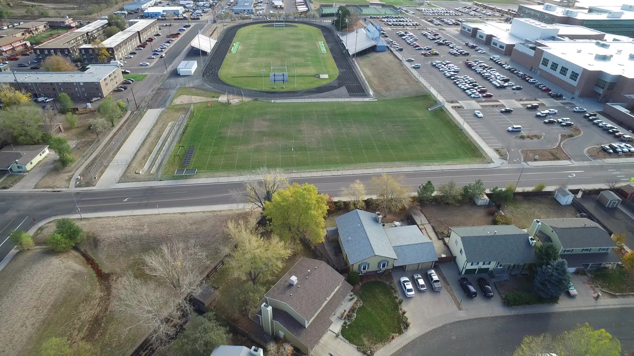 Aerial view of athletic fields, a running track, roads, parking lots, and nearby homes.