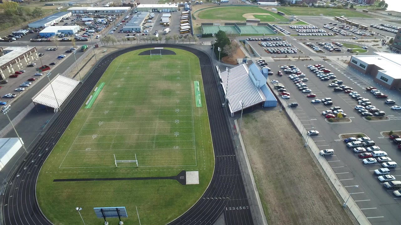 Aerial view of a football field inside a running track beside parking lots.