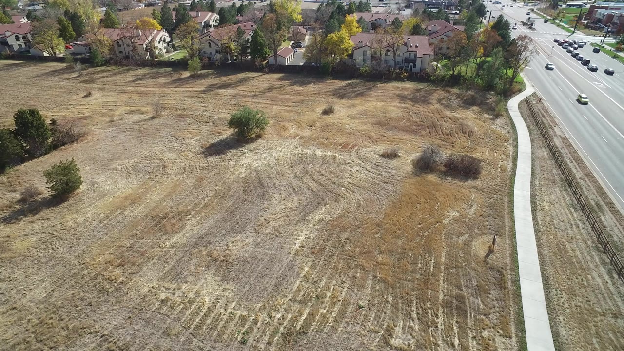 Aerial view of dry open field beside road and houses