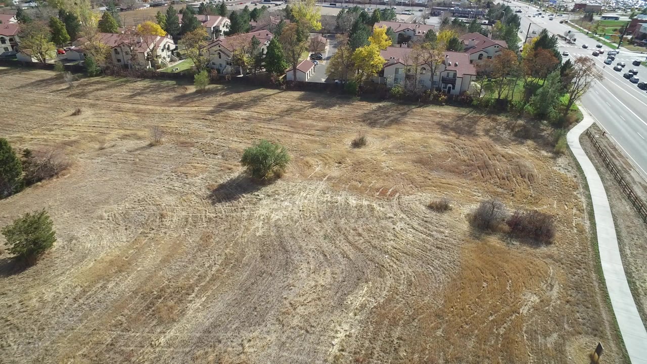 Aerial view of a dry empty lot beside houses and a road.