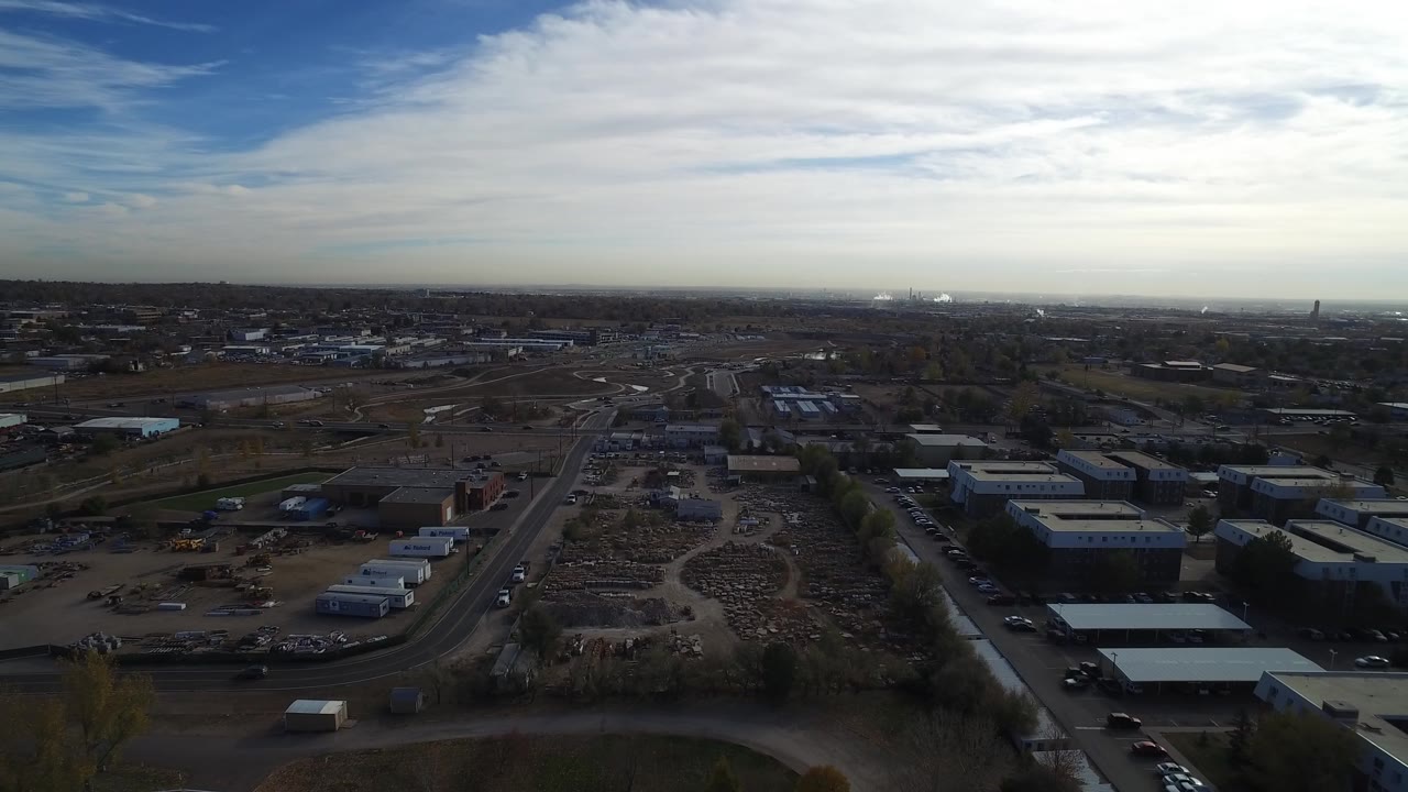 Wide aerial frame over Hidden Lake, Colorado, showing low buildings, open dirt lots, roads, sparse vegetation, and no visible people at the start of the clip.