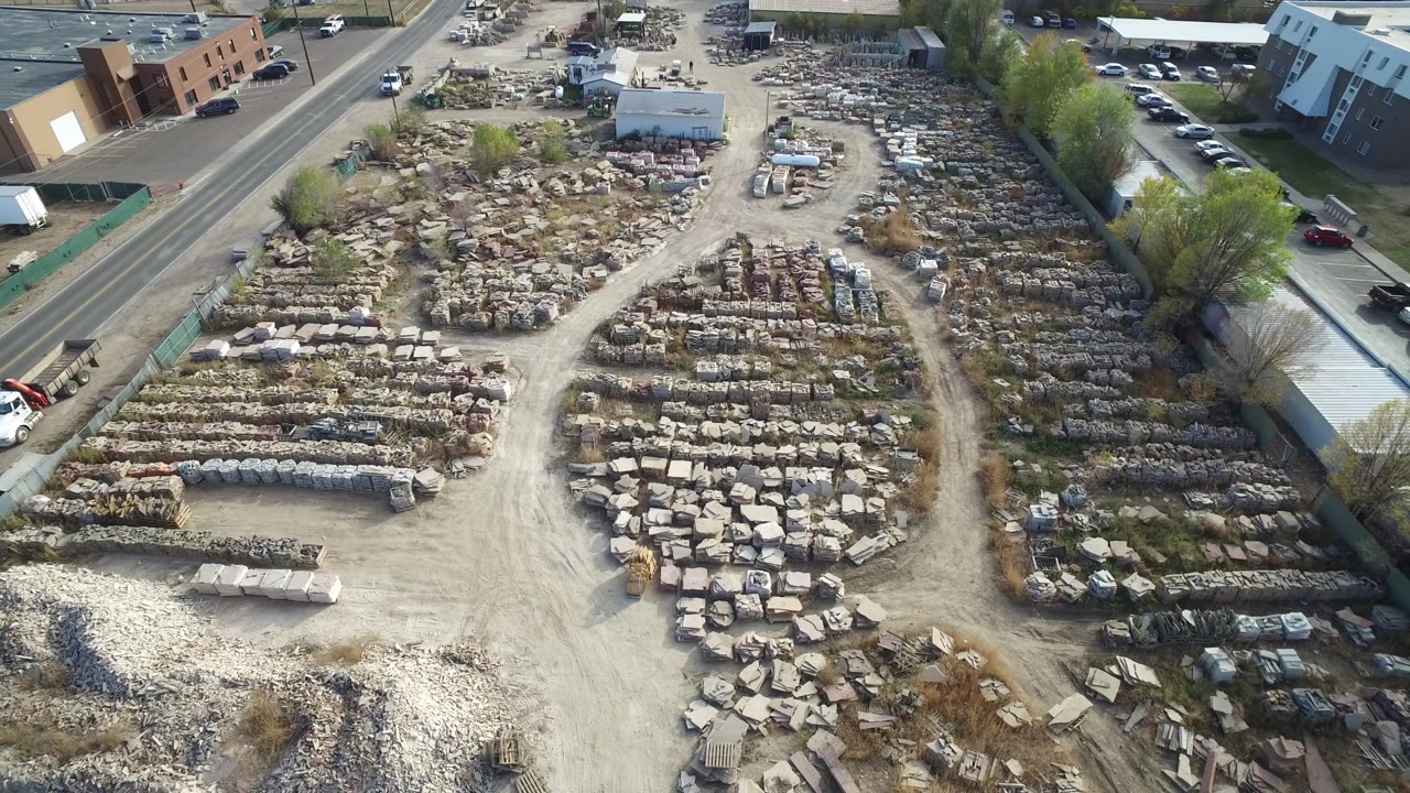 Aerial yard scene with large stone stacks and a road along the left side.