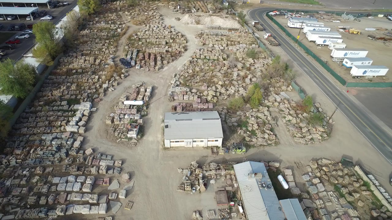 Second frame of the Hidden Lake aerial shows the same storage yard from above, with the road and branded-looking white trailers more prominent along the upper right edge, and no visible people.