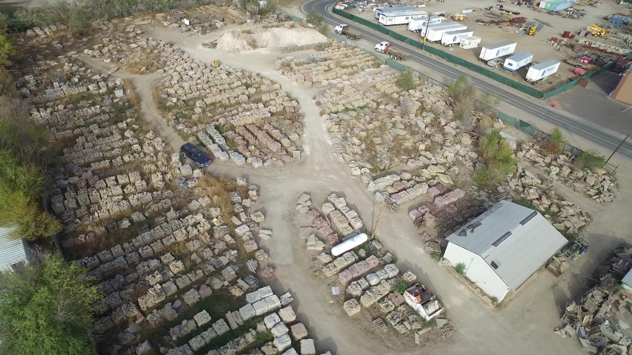 Aerial view of storage rows, warehouse building, road, trees, and open lots.